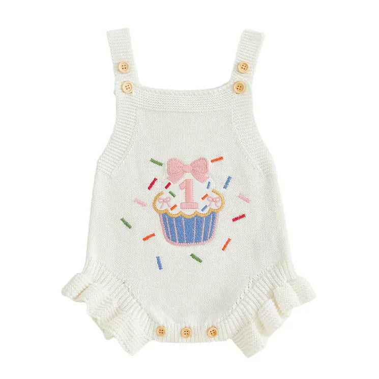 Pink knit first birthday romper with embroidered cupcake sprinkle design, ruffle hem and adjustable button straps