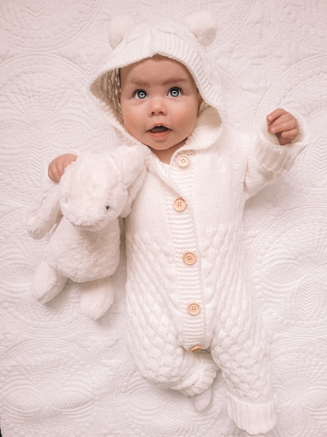 Baby wearing our white knit bear onesie with pom-pom ears. Adorable and cozy unisex baby outfit.