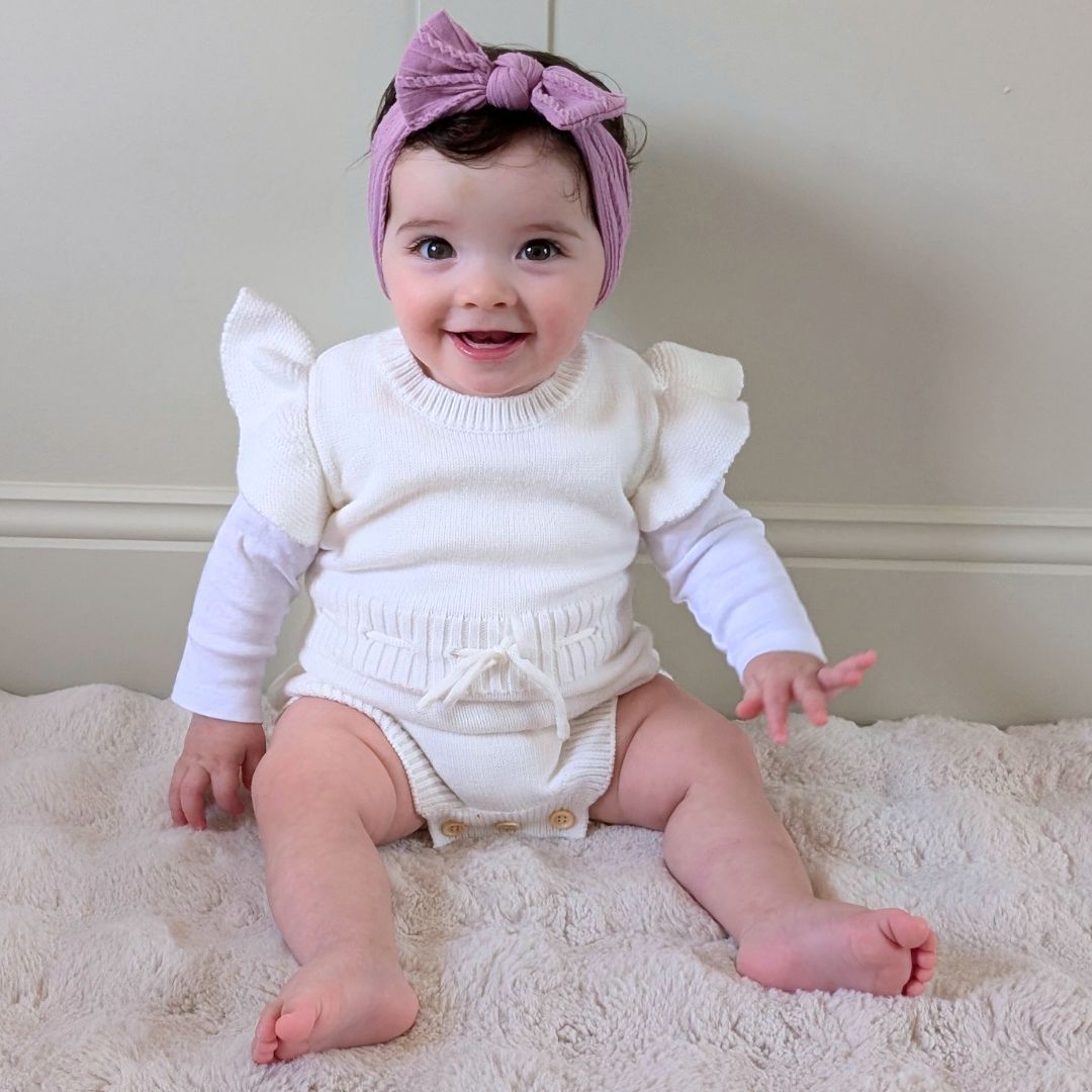 Cute baby girl wearing knit ruffle romper in white from Lulu Babe