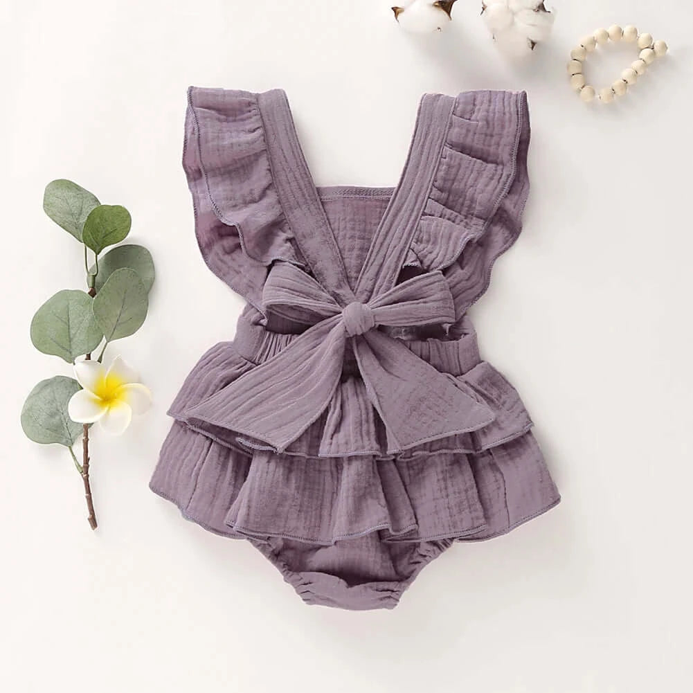 Back view of Jennifer Ruffle Baby Girl Romper in mauve styled flat lay