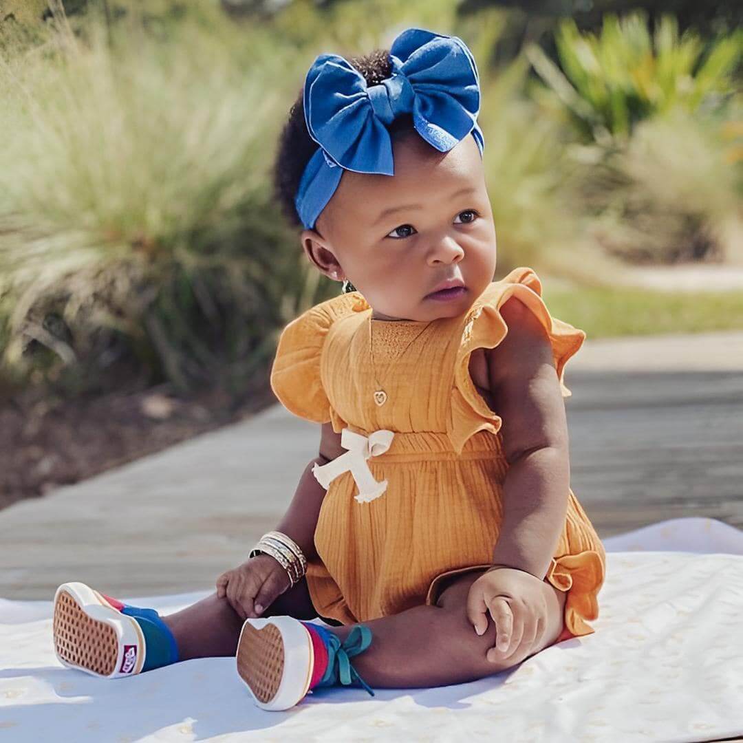 Baby girl wearing ruffle baby girl romper, sitting in park