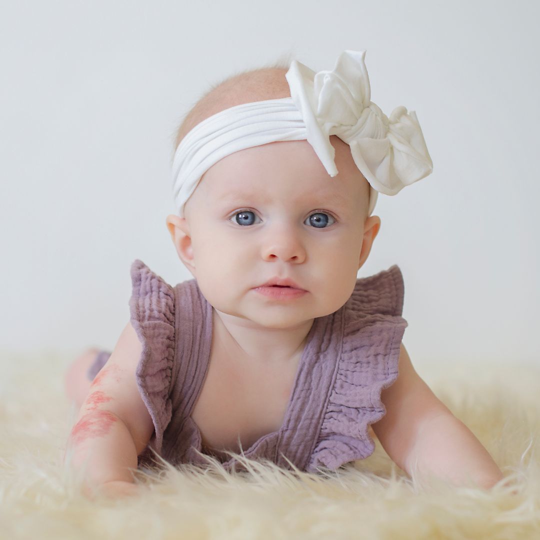 Baby girl wearing willow ruffle romper in lilac for photo