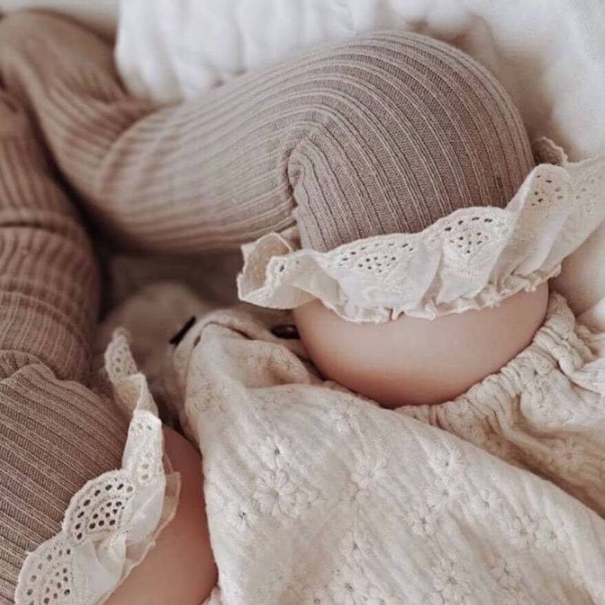 Baby wearing frilly vintage lace knee high socks in brown