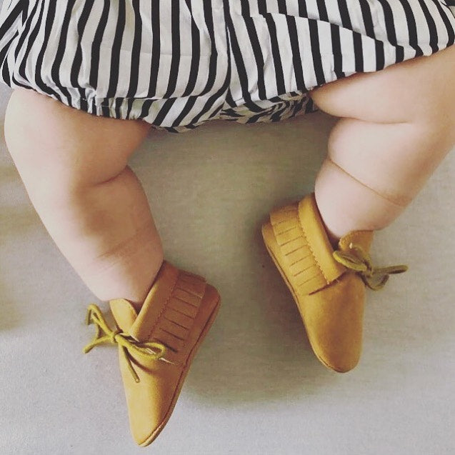 Baby modelling lace-up baby moccasins in mustard