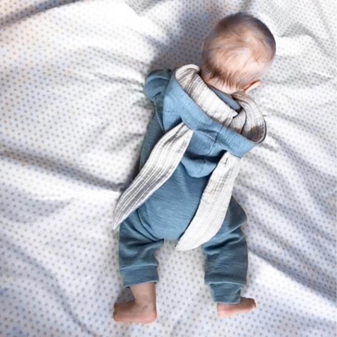 Baby wearing blue bunny onesie with floppy ears on hood
