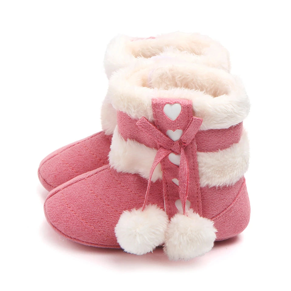 Rose pink baby slipper boots with plush lining, heart detailing and fluffy pom poms