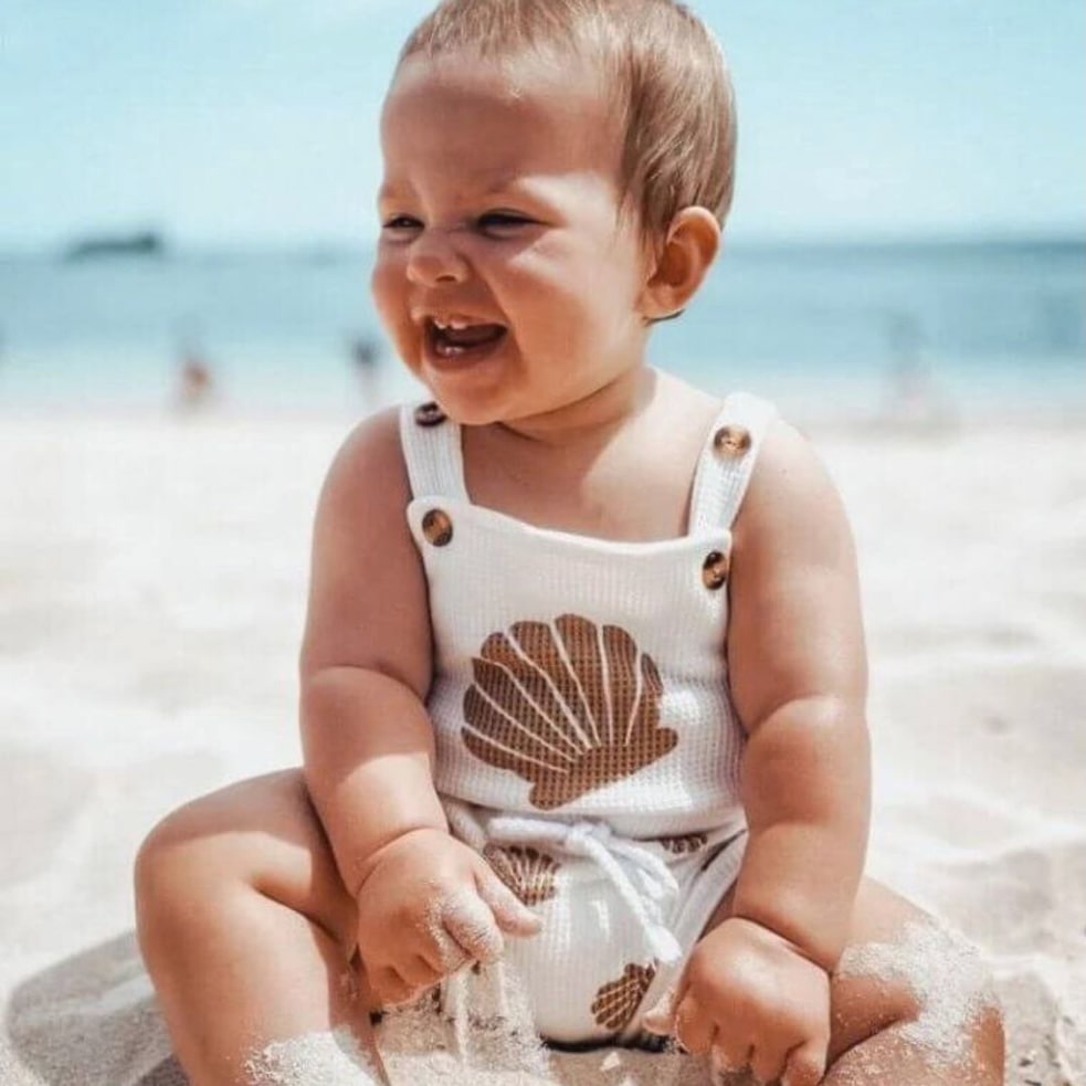 Happy baby at the beach, modelling summer baby clothes
