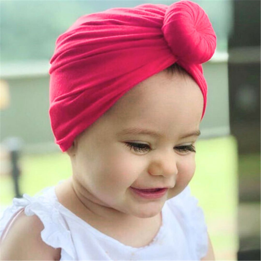 Baby girl in a fuschia top knot turban.