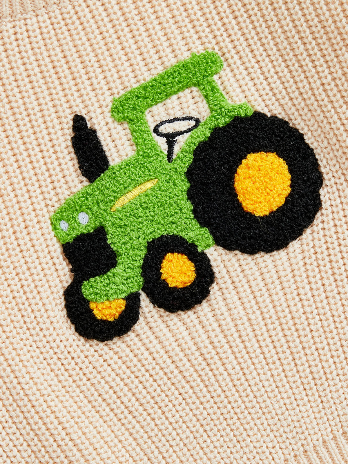Closeup of tractor design on beige toddler jumper