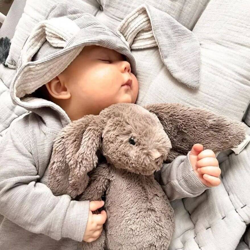 Baby wearing grey bunny onesie with floppy ears on hood