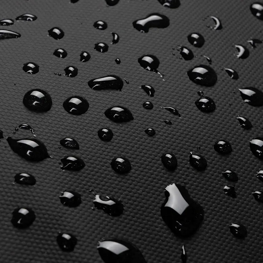 Close-up of water droplets on a black waterproof fabric, showcasing Finn backpack's water-resistant properties.
