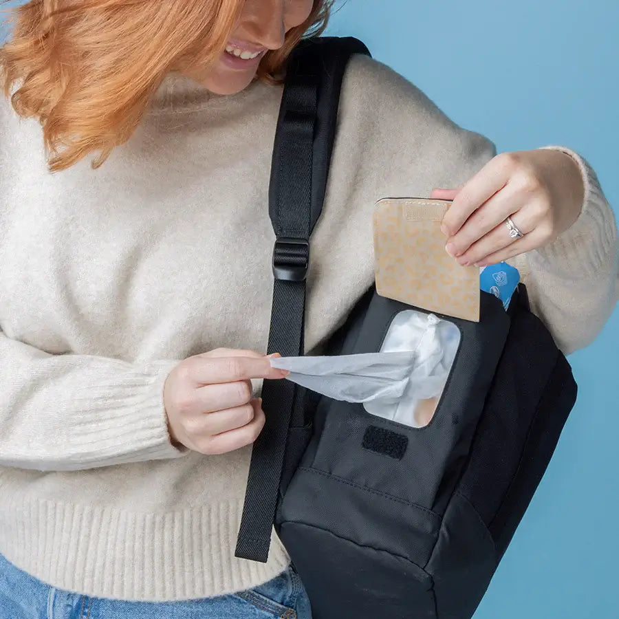Mum using Easy-wipes side pocket of the Babymel Finn nappy backpack in black.