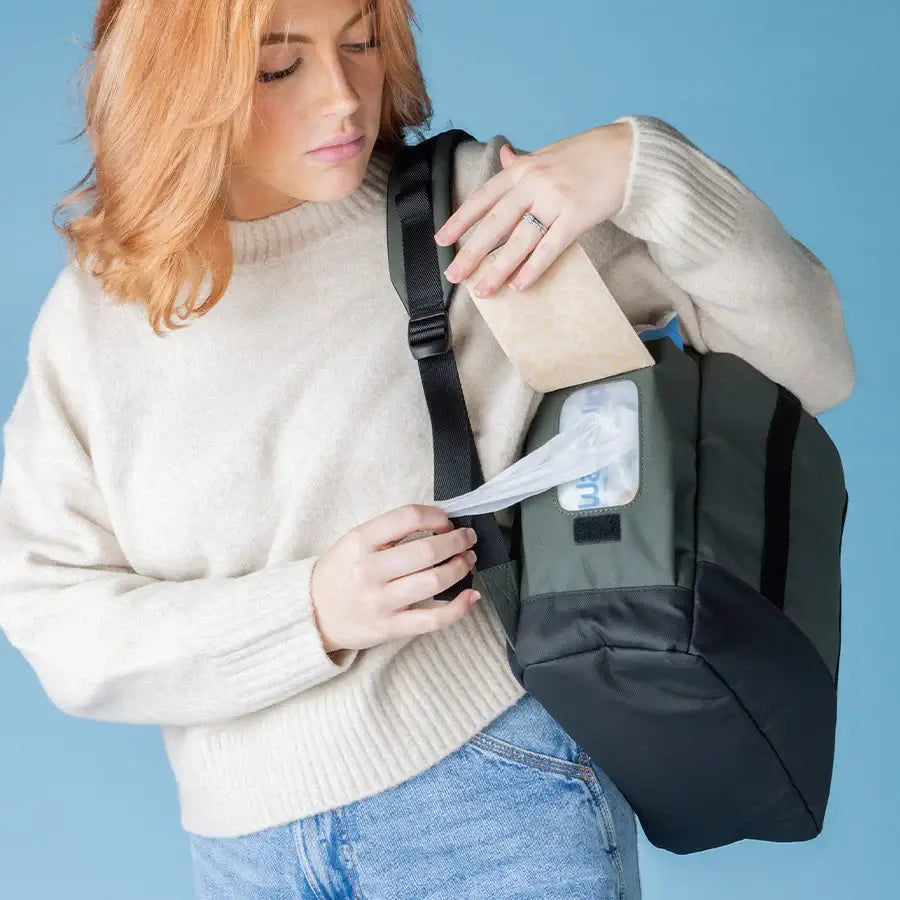 Mum using Finn nappy backpack's easy-access side wipes pocket (olive).