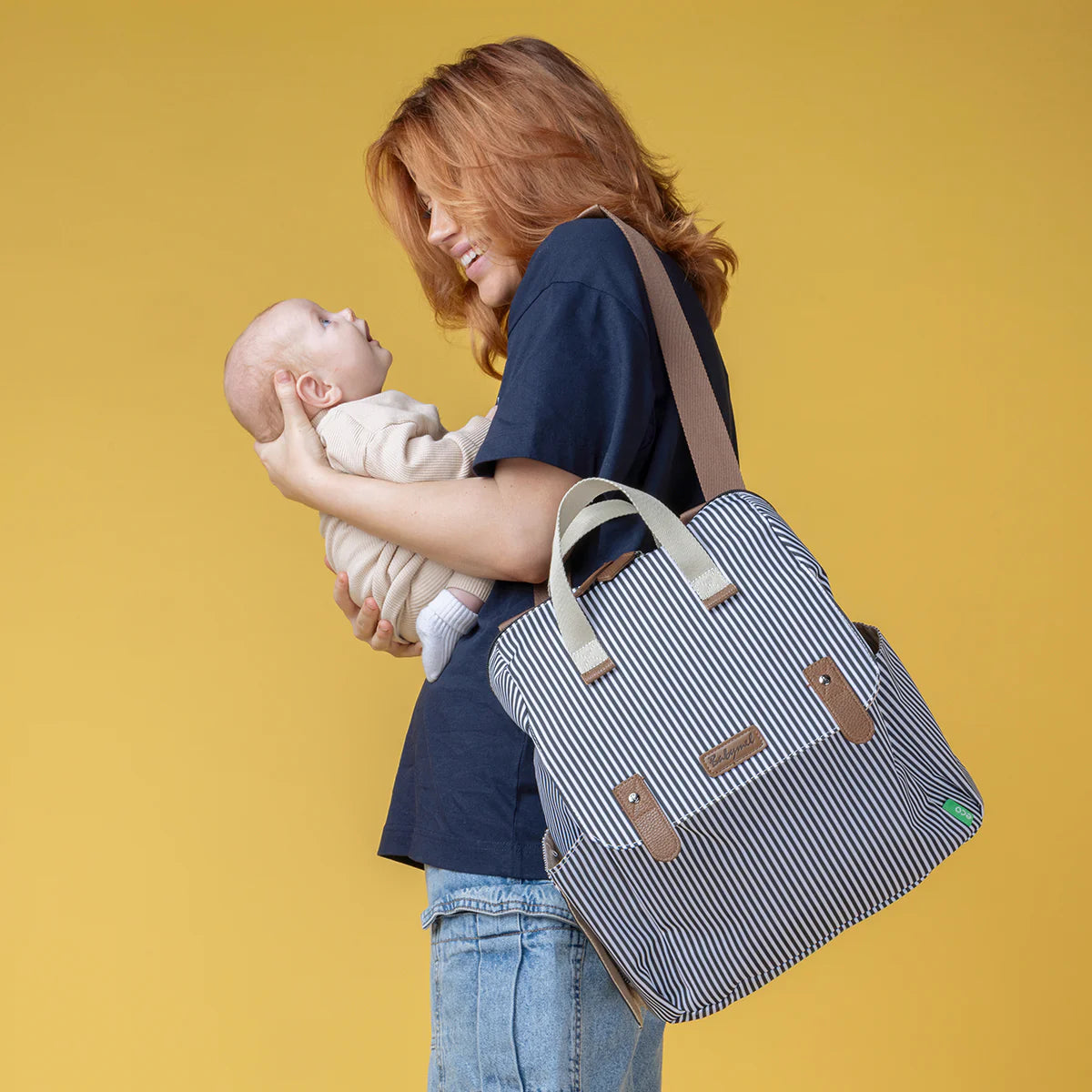Mum holding a baby and Babymel Robyn striped nappy backpack from Lulu Babe