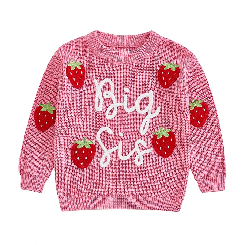 Pink chunky knit Big Sis jumper with embroidery script and strawberry appliqués, flat lay on cream background