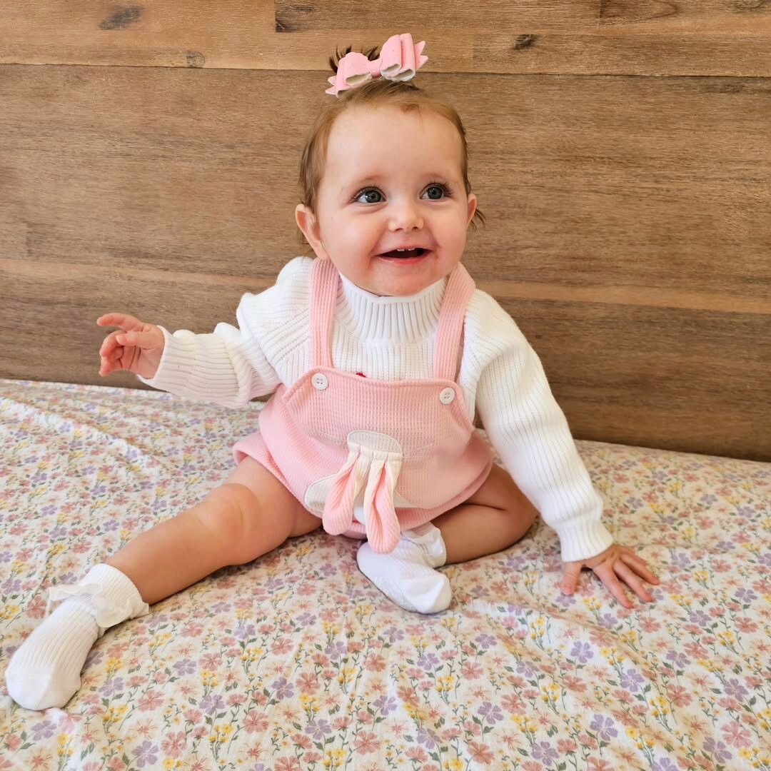 Smiling baby girl wearing bunny waffle romper in pink