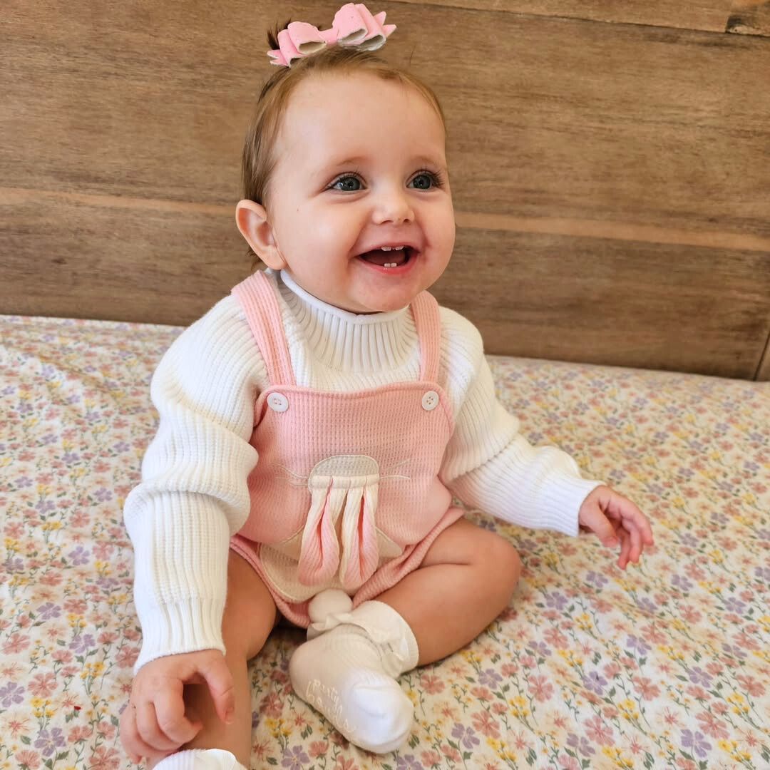 Smiling baby girl wearing bunny waffle romper in pink