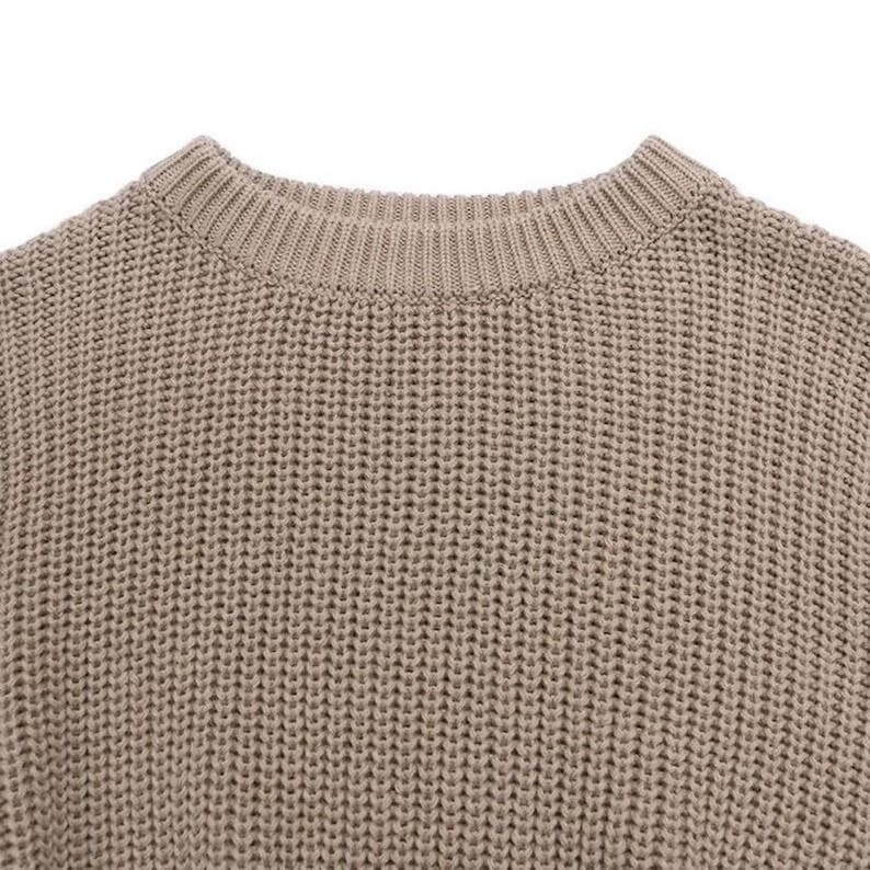 Knitted baby jumper in taupe - closeup showing the knit fabric.