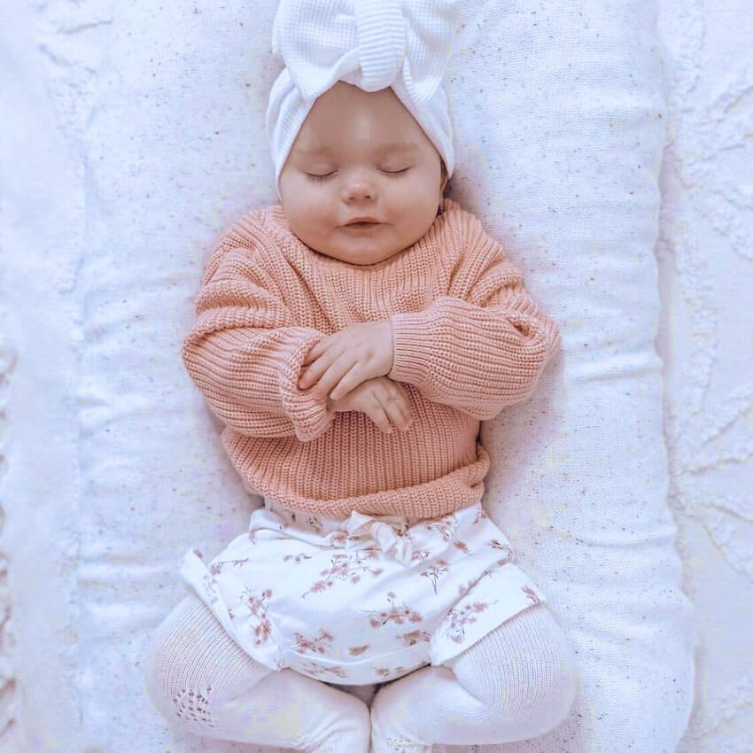 Sleeping baby girl wearing our pink knitted baby jumper