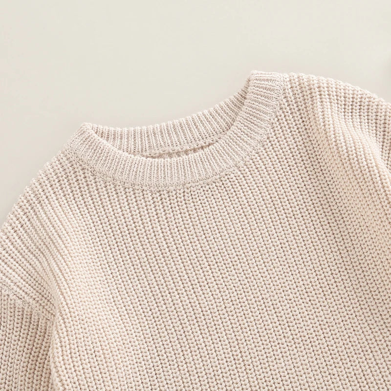 Close-up of a chunky knit baby romper in oatmeal