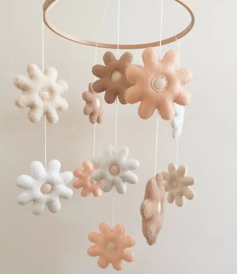 Daisy baby cot mobile featuring soft felt flowers in neutral tones for nursery decor, adding charm to baby's space.