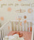 Daisy baby cot mobile with soft felt flowers above a sleeping newborn in a cozy nursery.