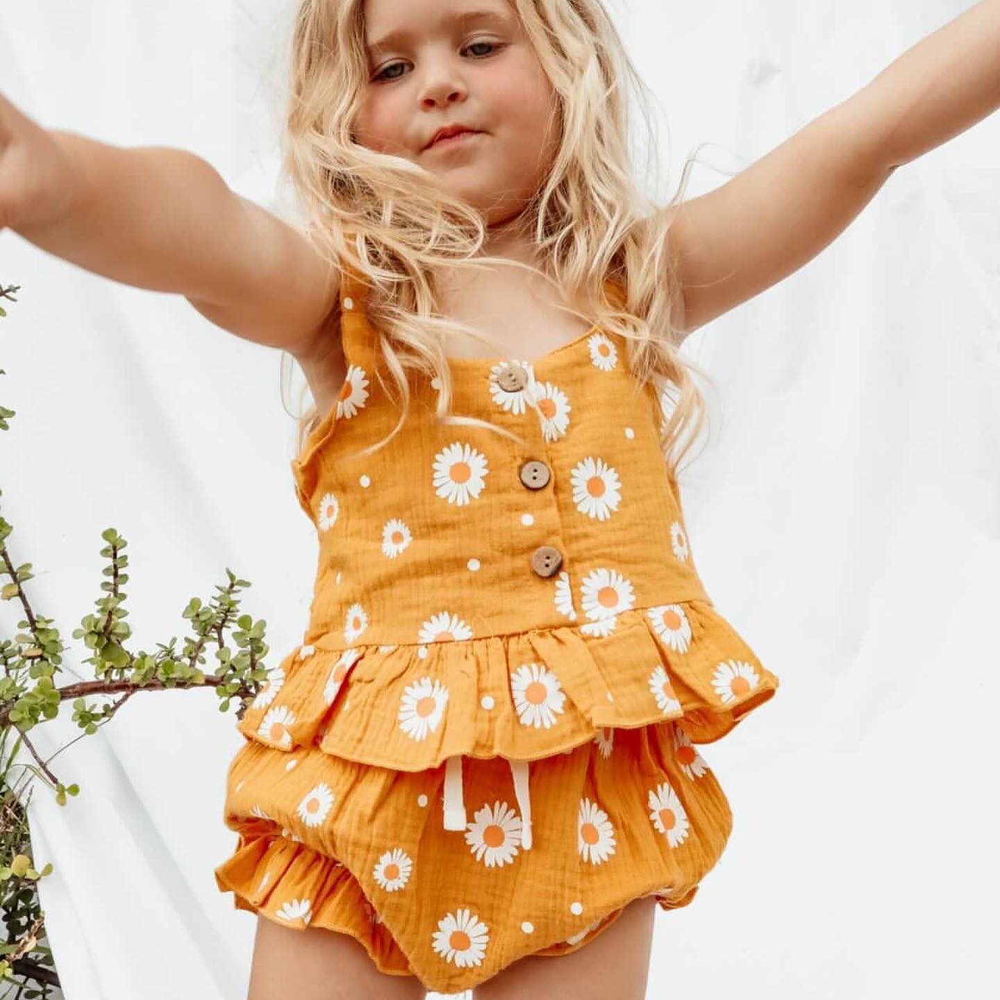 Girl wearing yellow daisy toddler girl outfit - peplum top and matching shorts
