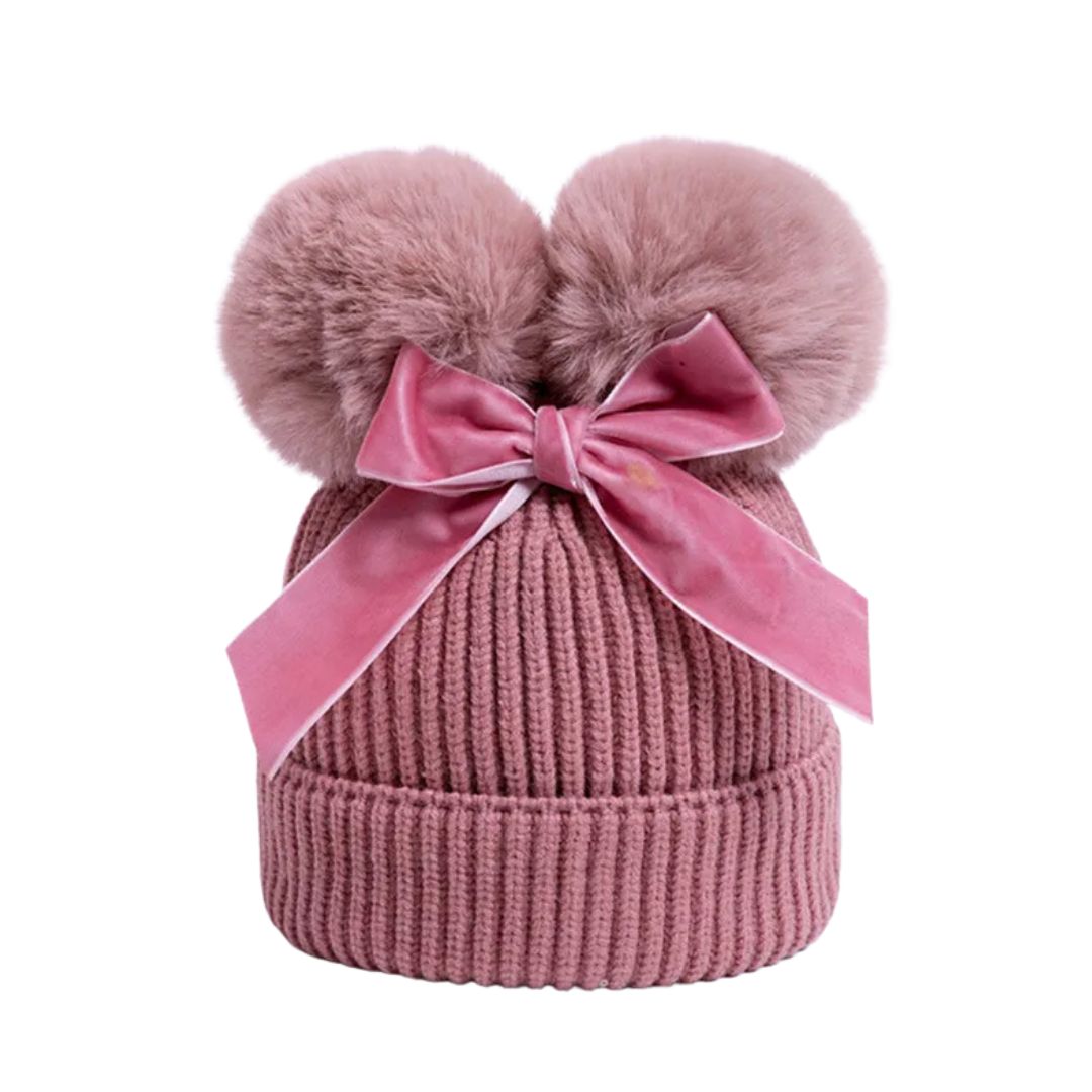 Pink knit beanie with two fluffy pom-poms and a large pink velvet bow