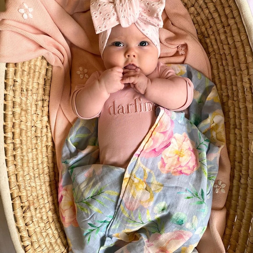 Adorable baby swaddled in a Floral Muslin Wrap, featuring soft floral patterns, perfect for keeping little ones snug.