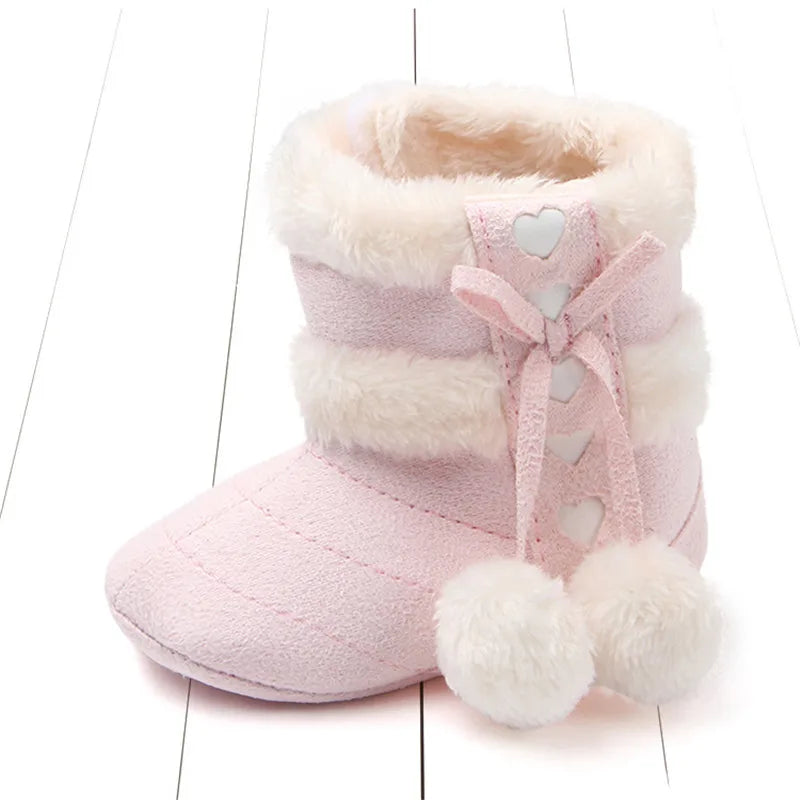Blush baby slipper boots with faux fur lining, heart detailing and fluffy pom poms