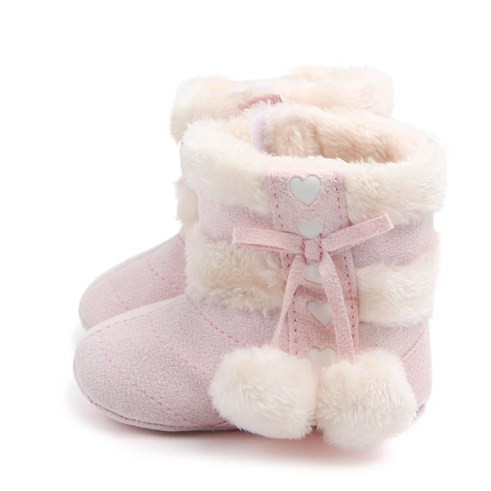 Baby winter boots in blush with plush lining, heart detailing and fluffy pom poms