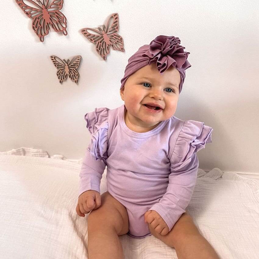 Baby girl wearing our flutter bodysuit in lilac and ribbed ruffle turban