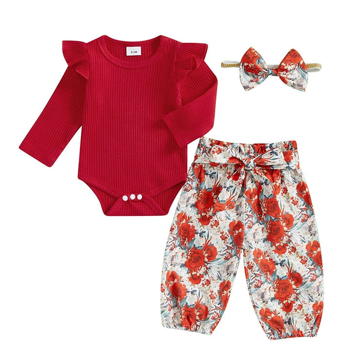 3-piece Holly Flutter Set Christmas baby girl outfit featuring a long-sleeve red ribbed bodysuit with ruffle shoulders, floral harem pants with a tied waist bow, and a matching floral bow headband