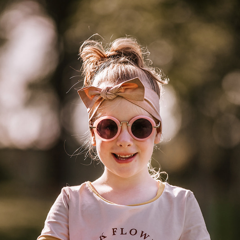 Girl wearing round  pink retro sunglasses with UV400 lenses