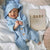 Smiling baby boy wearing our Knit Baby Bear Onesie in blue