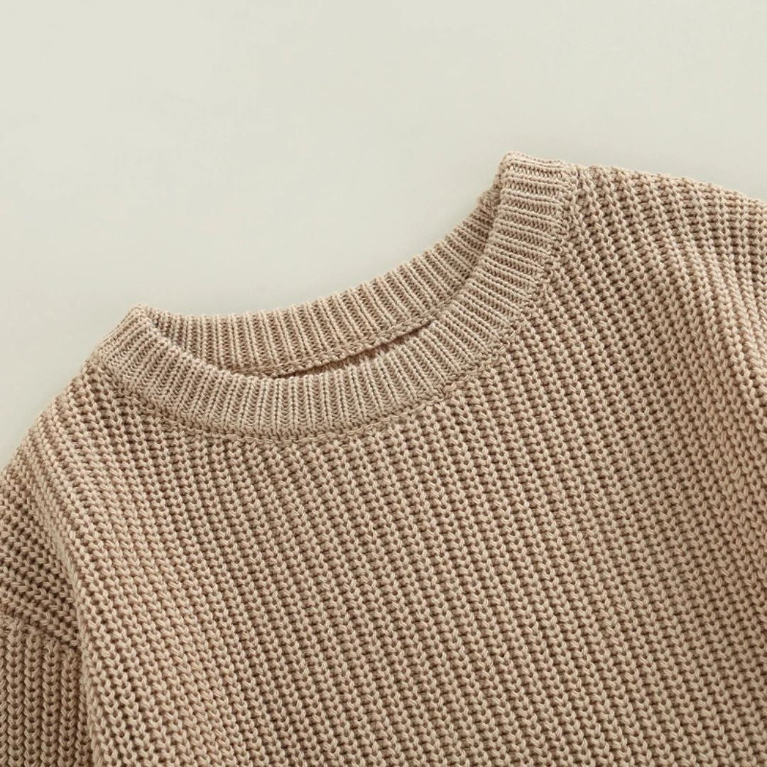 Close-up of a soft, chunky knit baby romper in latte, perfect for winter warmth and comfort for little ones.