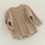 Knitted baby romper in latte, perfect winter outfit for babies, with long sleeves and button closures.