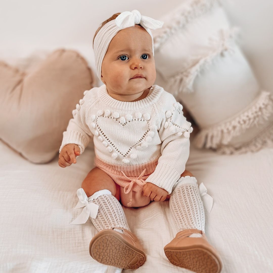 Baby girl wearing pink knit heart baby romper from Lulu Babe