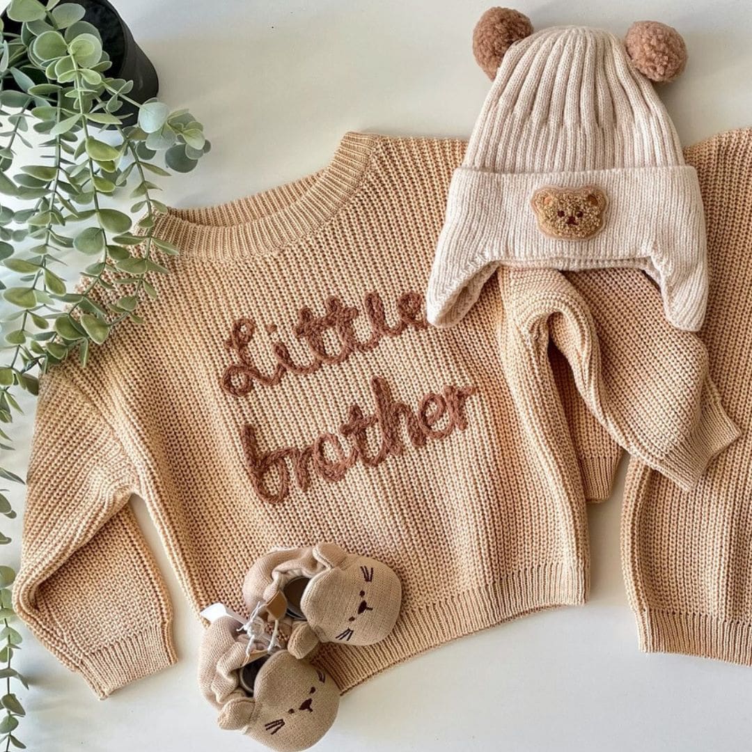 Styled flatlay of Little Brother knit jumper, baby booties & beanie | Lulu Babe