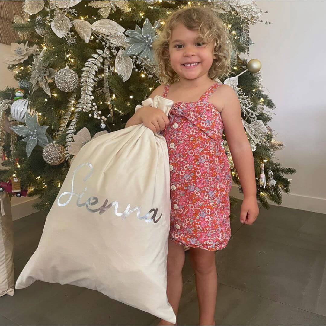 Girl holding her personalised Santa Sack in cream (also in blush, green, red, lilac, silver & navy) - Lulu Babe