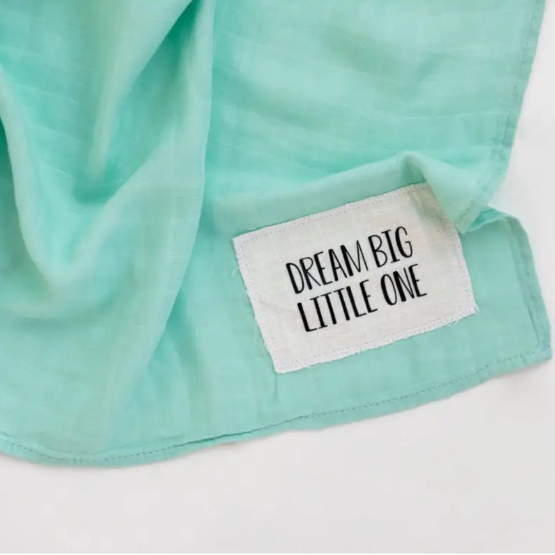 Dream Big Mint Muslin Swaddle Blanket with patch reading 'Dream Big Little One', ideal for baby comfort.