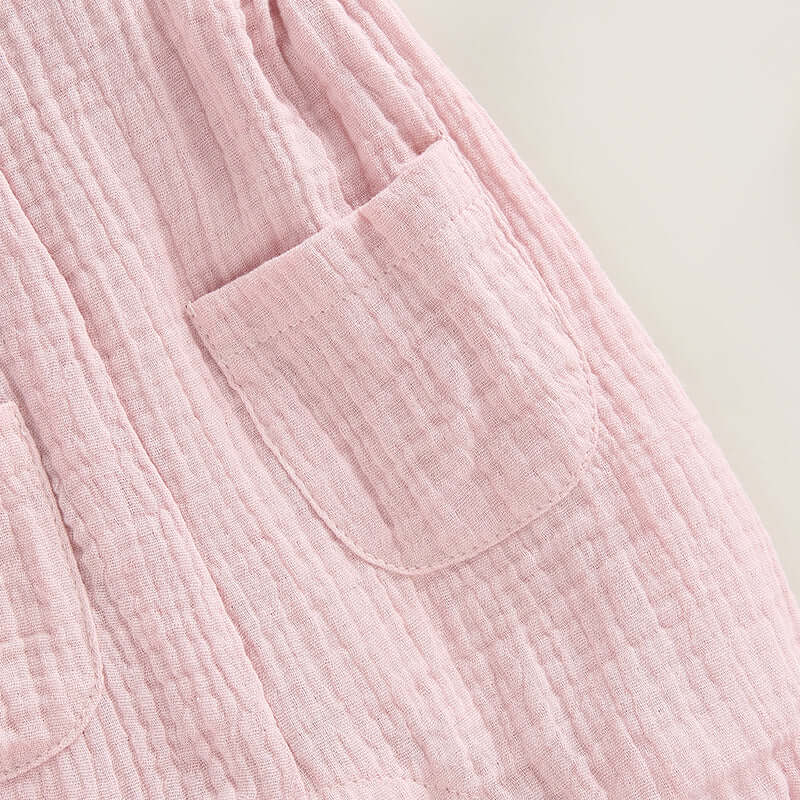 Cotton muslin baby romper in blush pink - closeup of front pockets