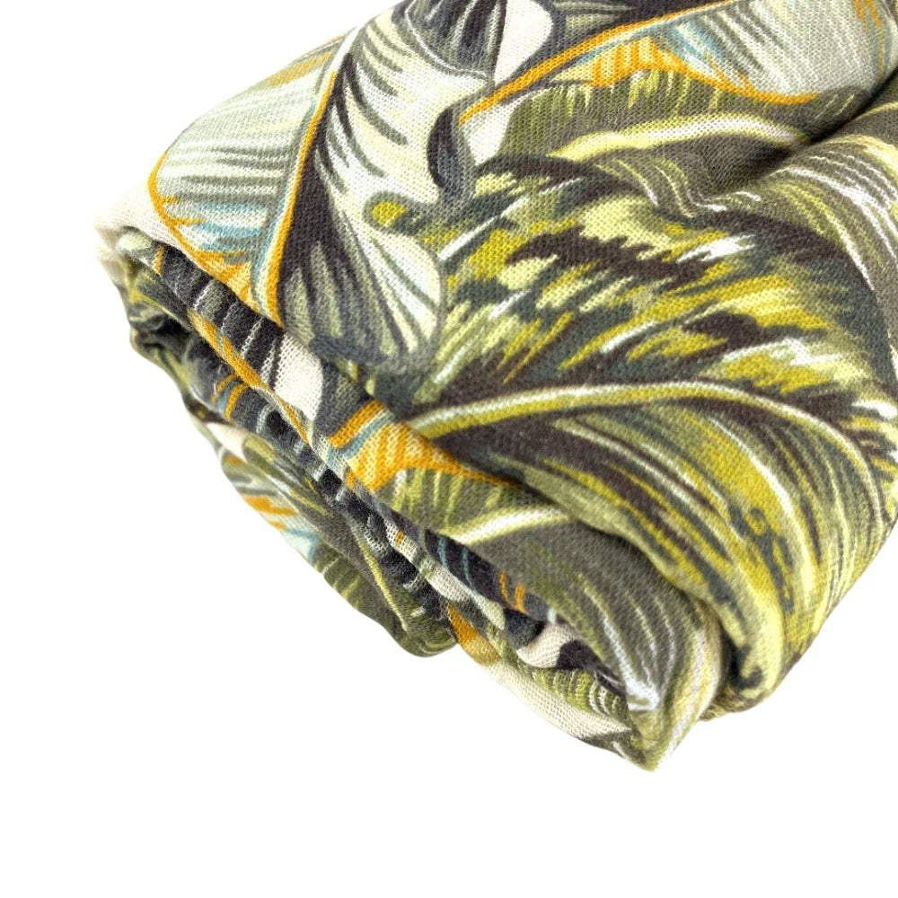 Closeup of muslin baby wrap in tropical leaf print by Little Renegade Company