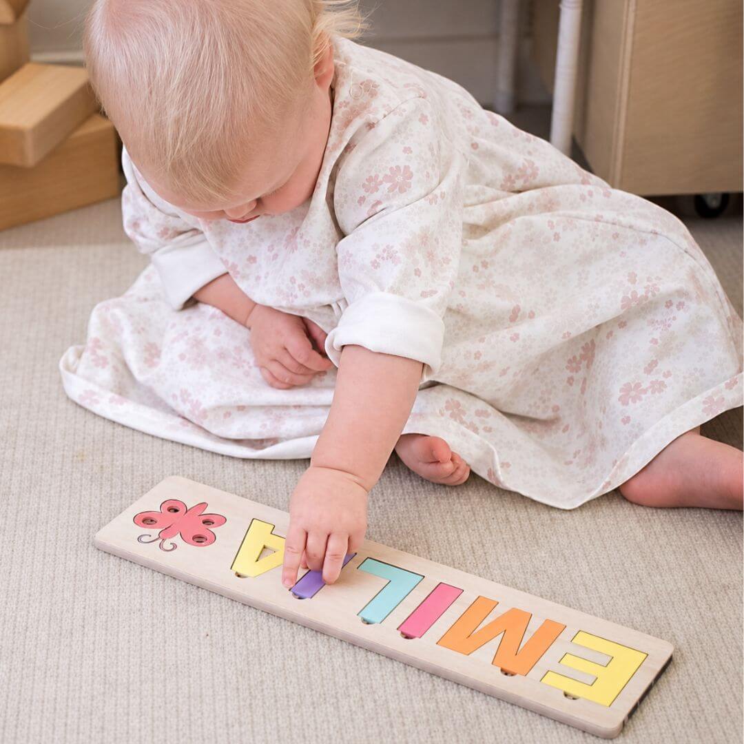 Baby girl playing with her custom-made name puzzle from Lulu Babe
