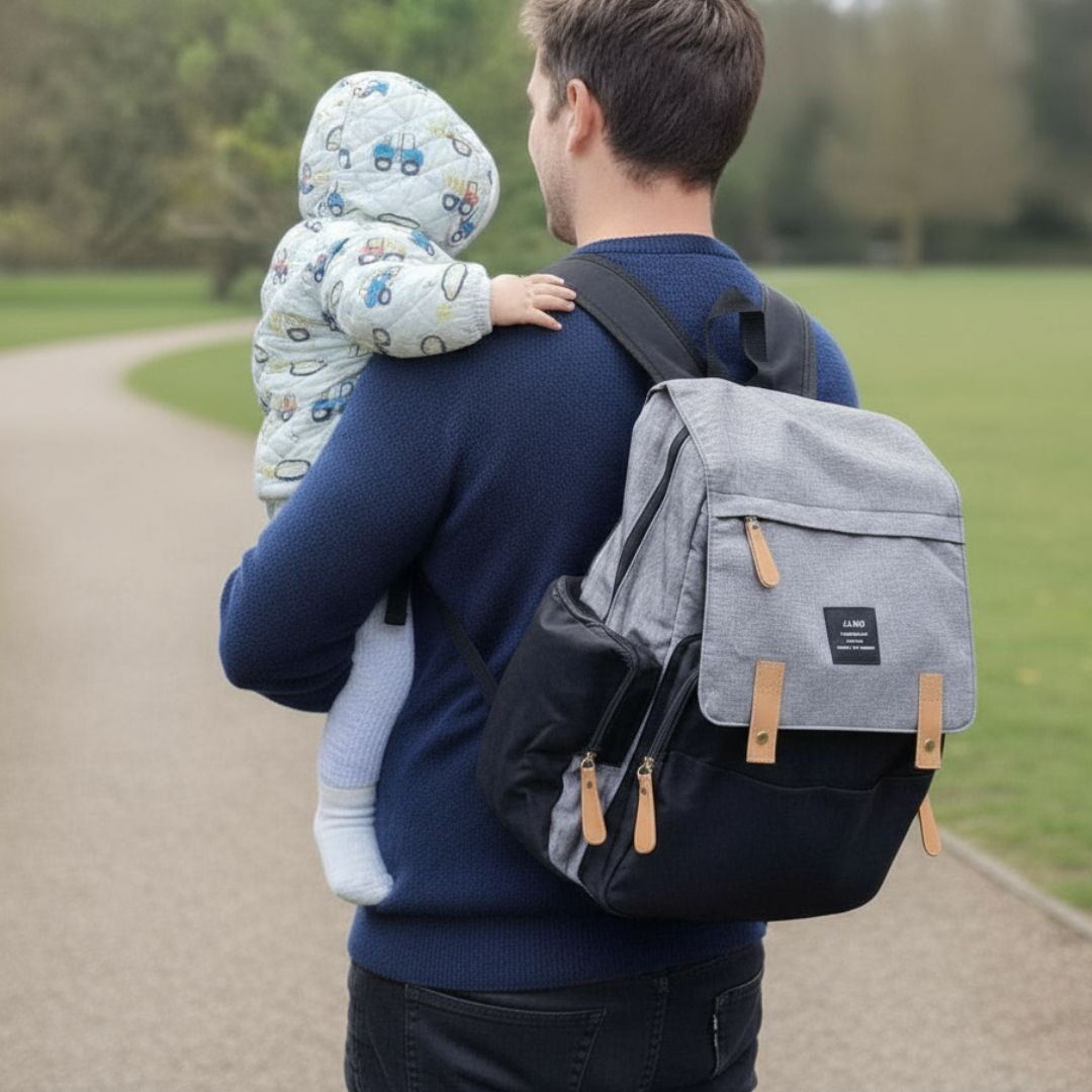 Dad holding baby wearing LAND nappy bag backpack in grey and black