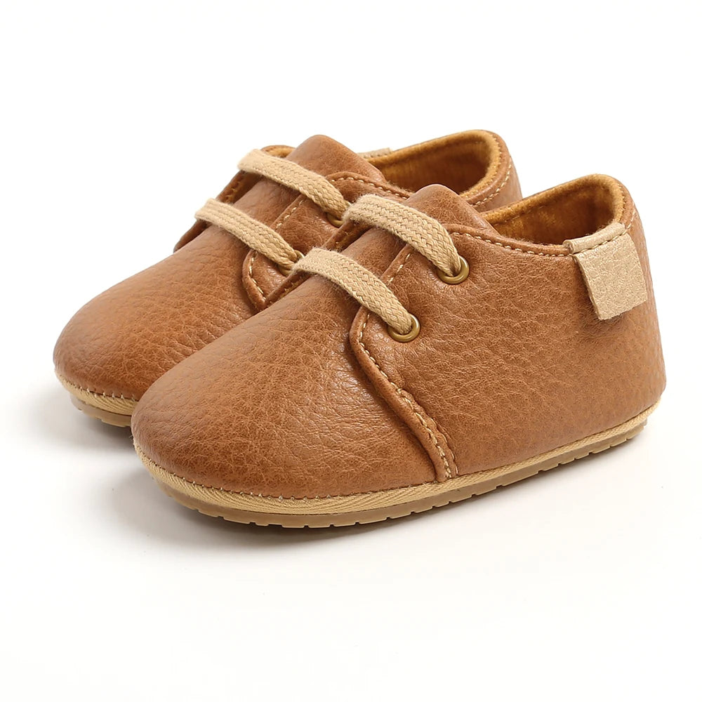 Tan faux suede lace-up oxford style baby shoes with non-slip sole, product shot on white background
