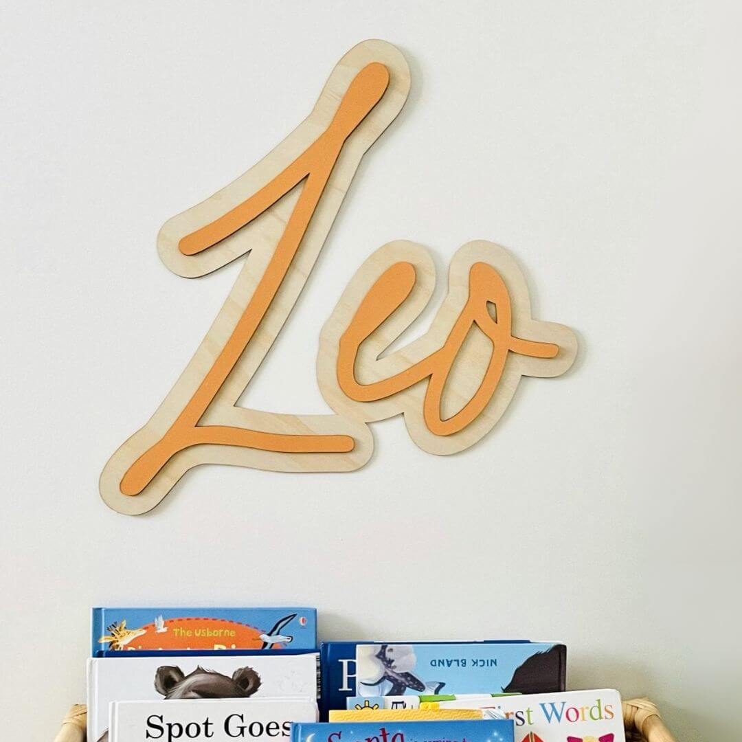 Personalised 3D layered wooden name sign reading Leo in orange acrylic lettering on natural plywood base