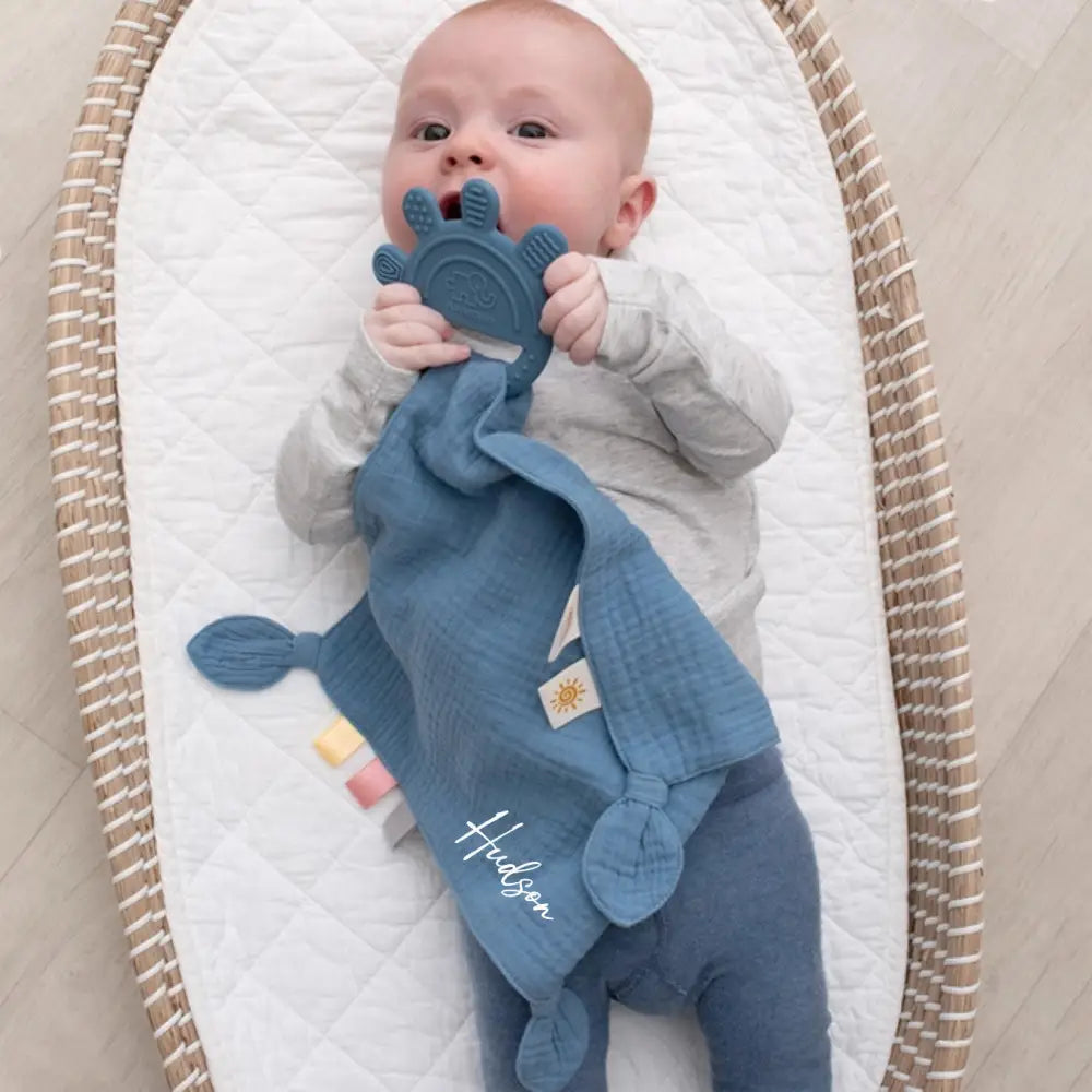 Baby playing with personalised muslin comforter with detachable silicone teether in blue