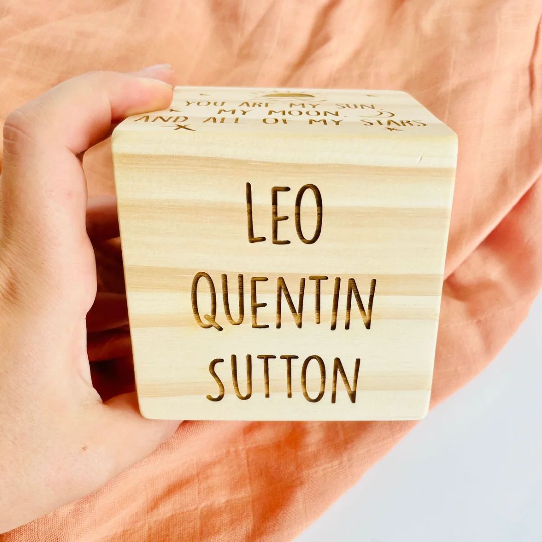 Personalised wooden birth stats block showing laser-engraved arrival date, time, weight and length on natural pine cube