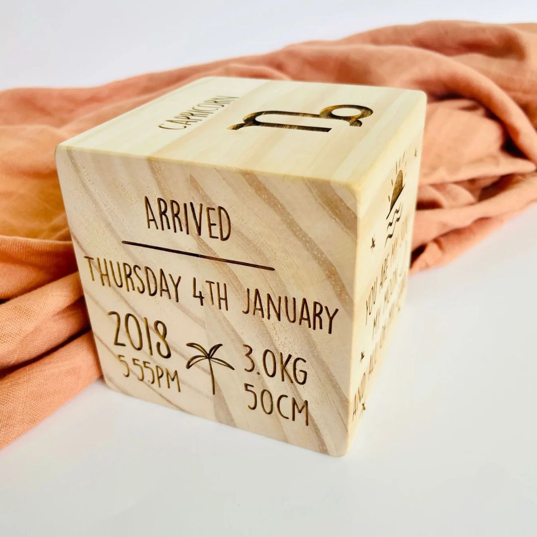 Personalised wooden birth stats block showing laser-engraved arrival date, time, weight and length on natural pine cube